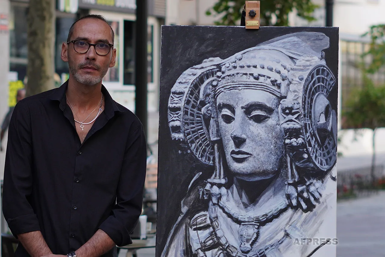 Daniel García junto a su pintura en blanco y negro de la Dama de Elche